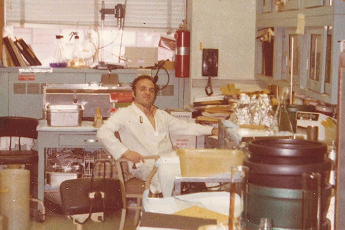 Robert Krug in a lab coat, sitting in his lab in the 1970s