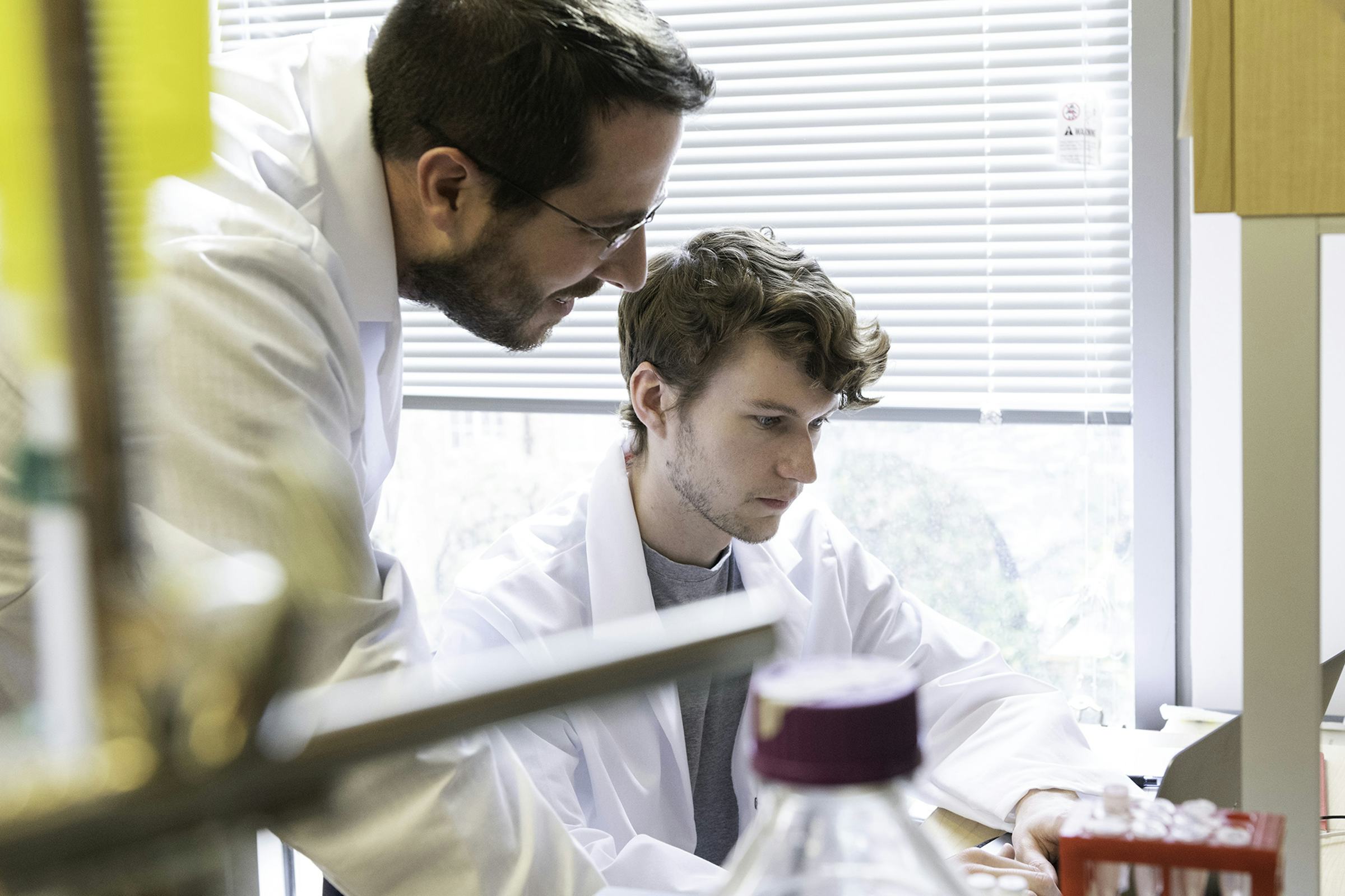 Two scientists, Jason McLellan and Daniel Wrapp, in white lab coats working in the lab