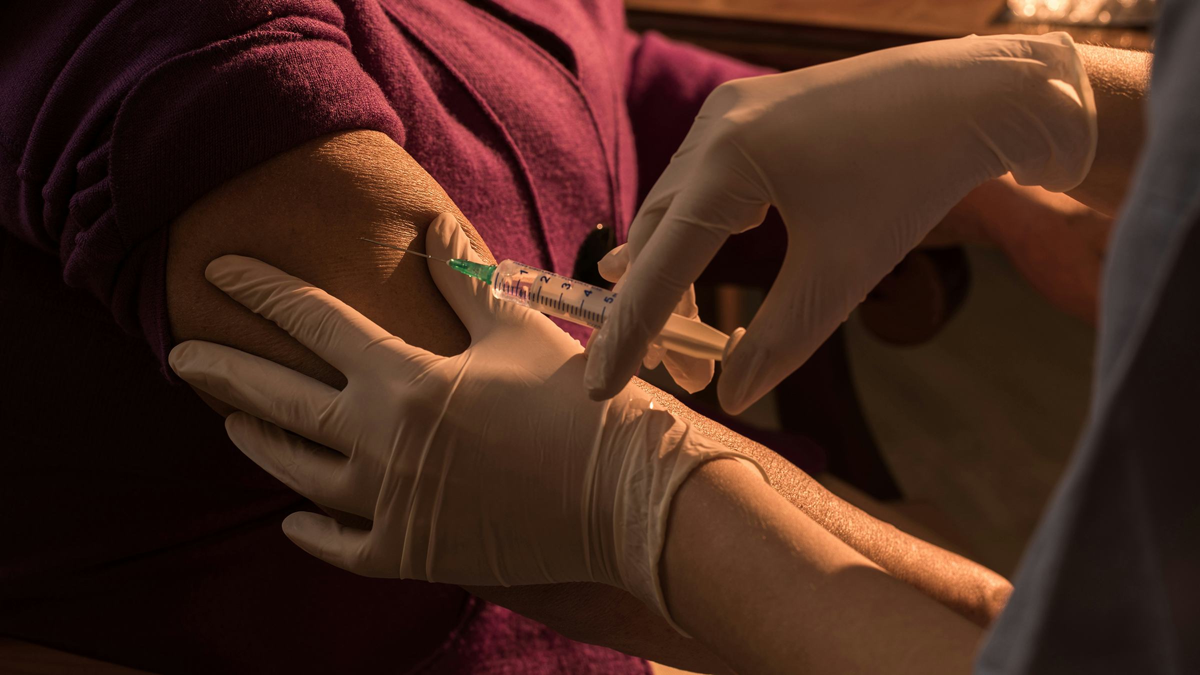 A doctor or nurse adminsters a vaccine in a patient's arm